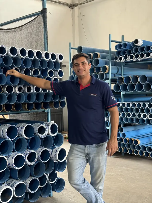 Vendedor da Perfurato ao lado das prateleiras de tubos de revestimento